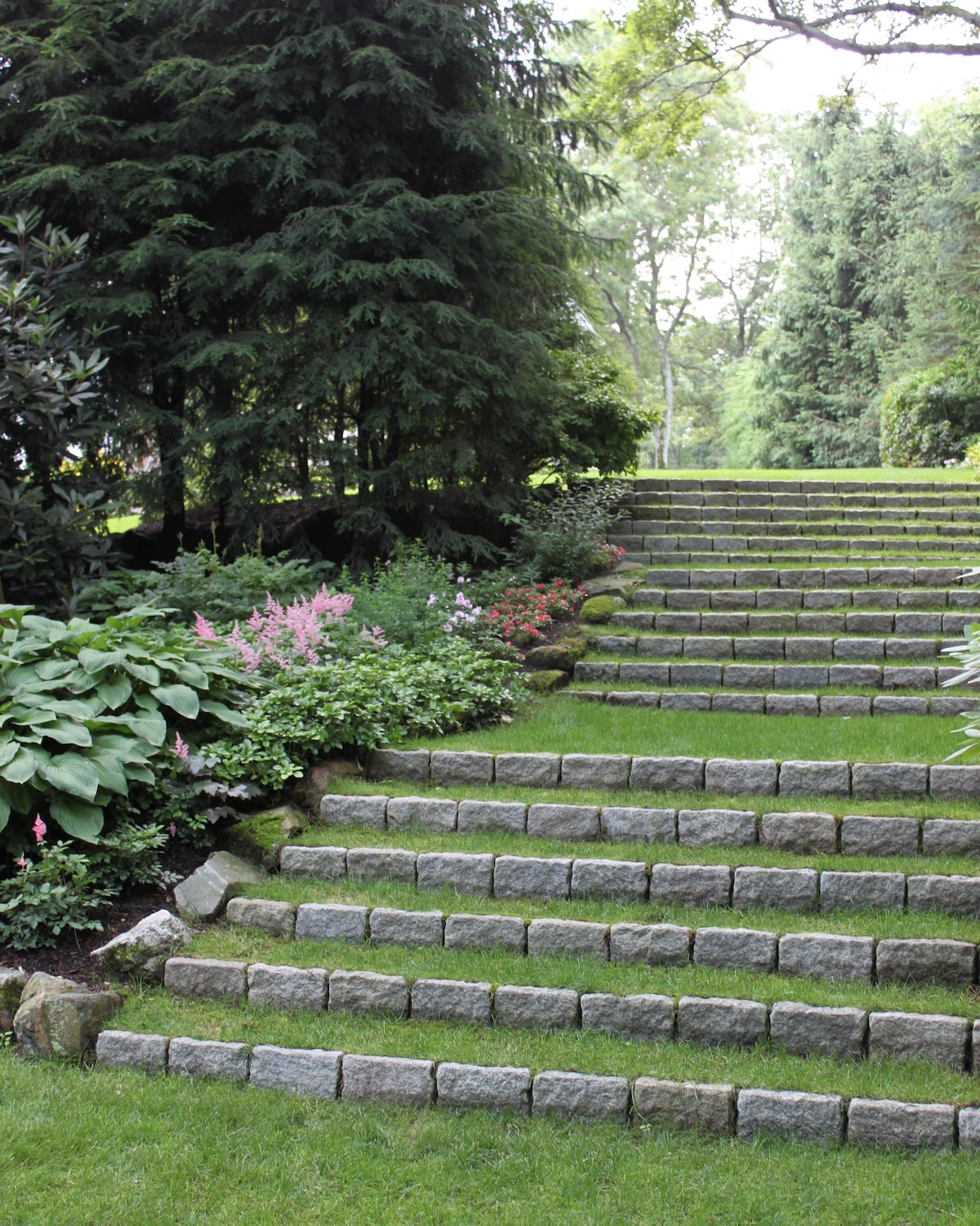 Grass covered steps for softening hardscaping elements in a home landscape.