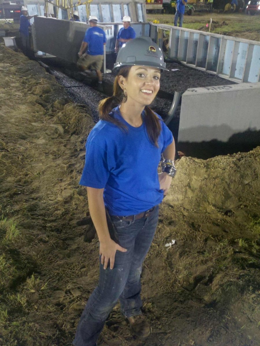 A smiling female project manager wearing a hard hat.