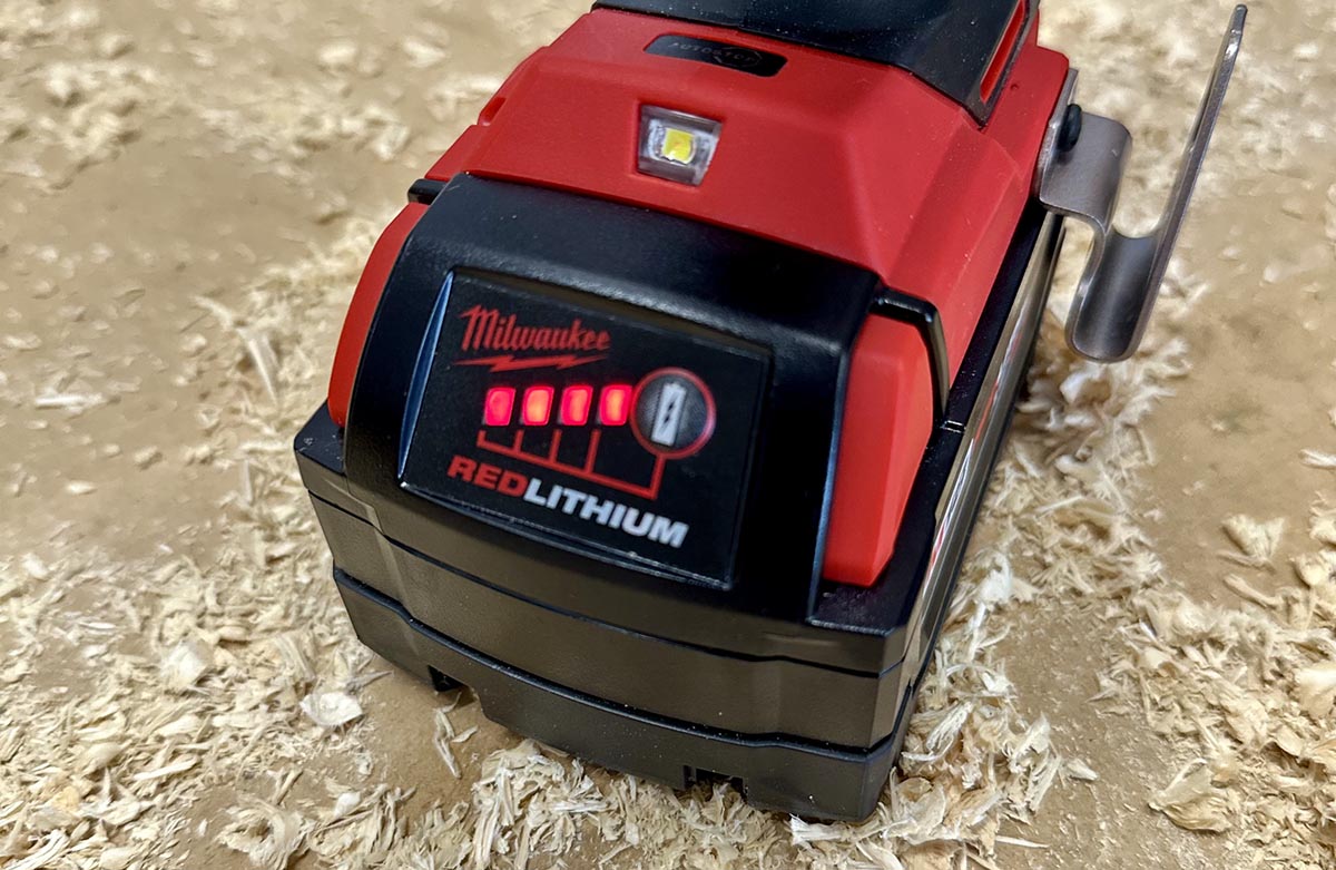 Charging station for Milwaukee tools batteries on a workbench with sawdust