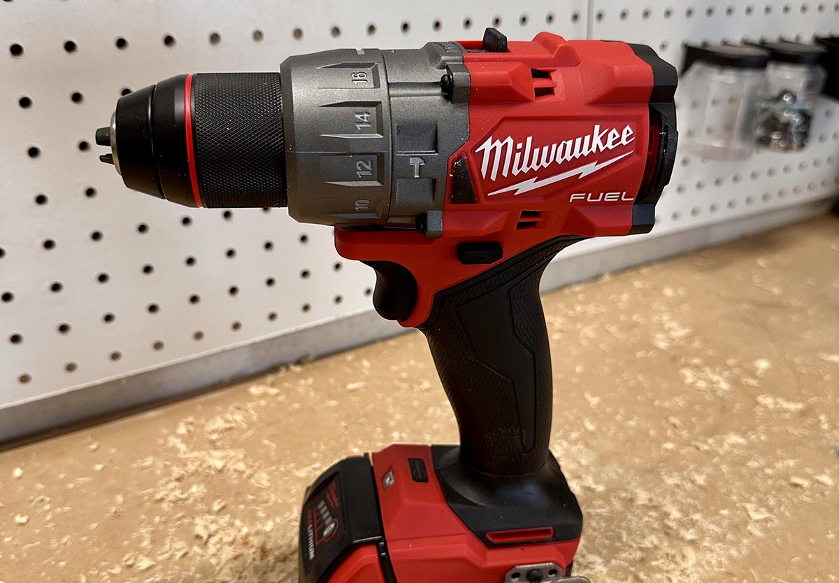 Milwaukee M18 Hammer Drill standing on its base on a workbench with sawdust