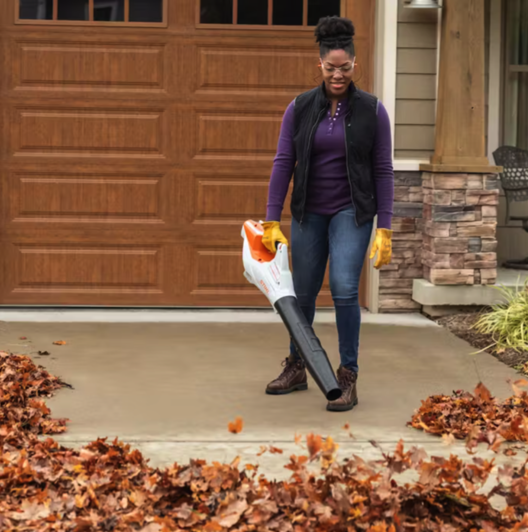 A woman using the Stihl BGA 86 leaf blower to clear a driveway