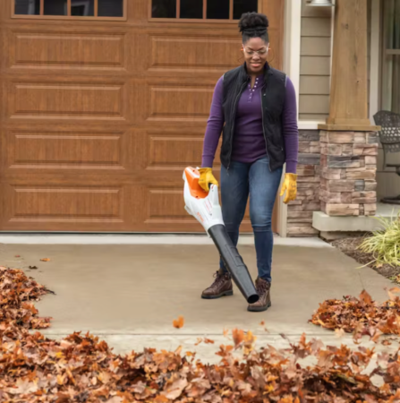 A woman using the Stihl BGA 86 leaf blower to clear a driveway