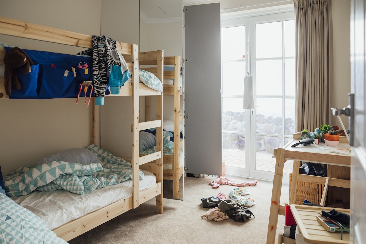 A messy child's bedroom with wooden bunkbeds.