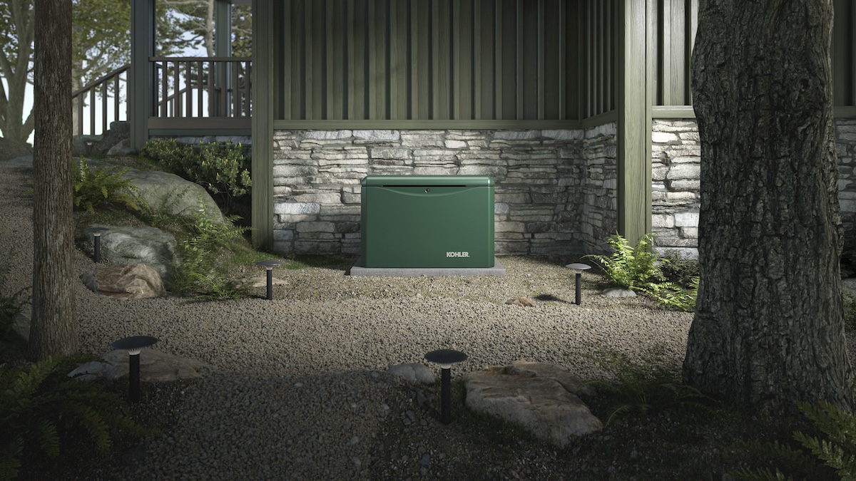 A dark green whole-house Kohler generator installed outside of a home.