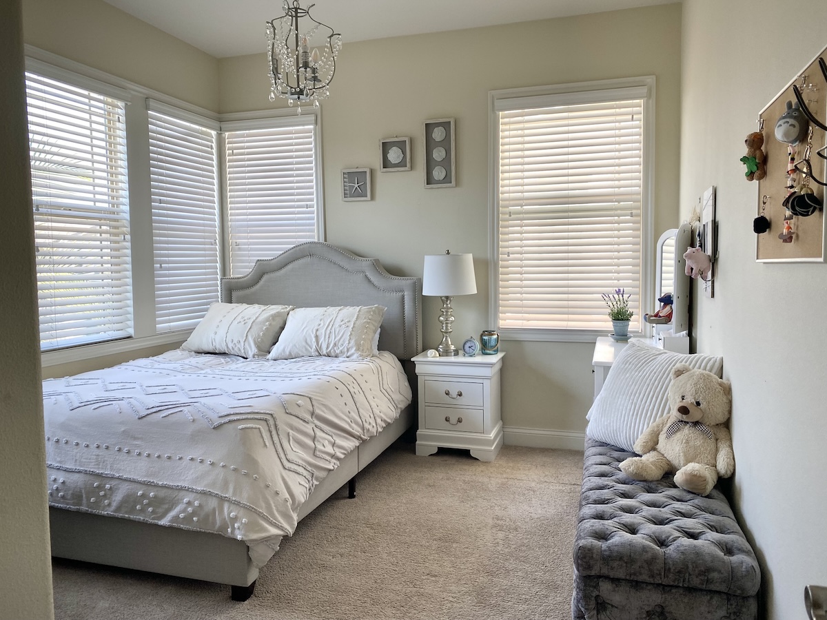 A grey and beige bedroom with carpet and a fireplace.