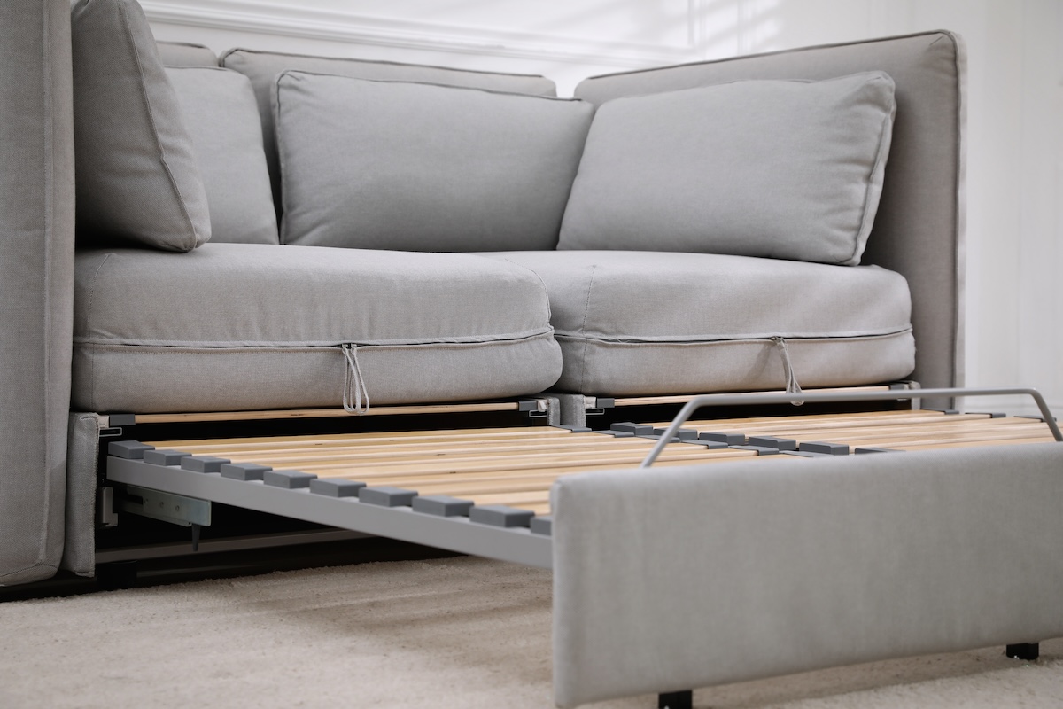 A grey sleeper sofa with wooden panels.