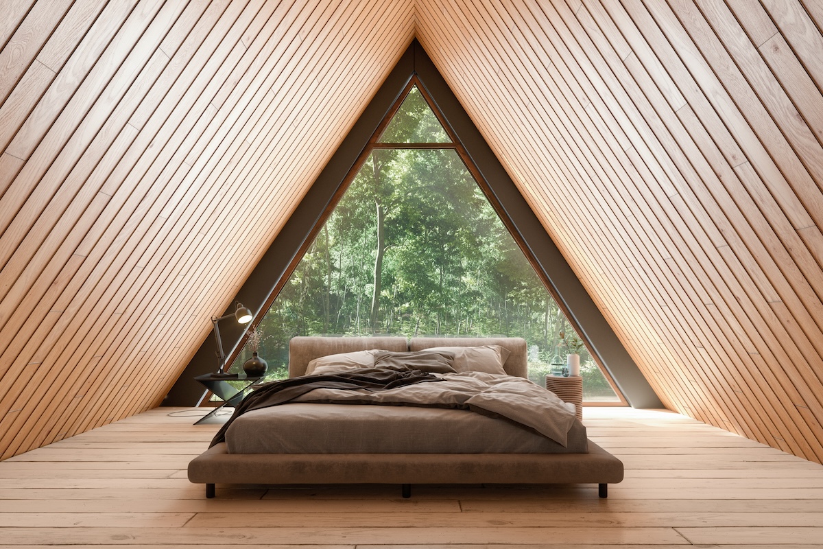 Wooden home with triangular ceiling in bedroom.