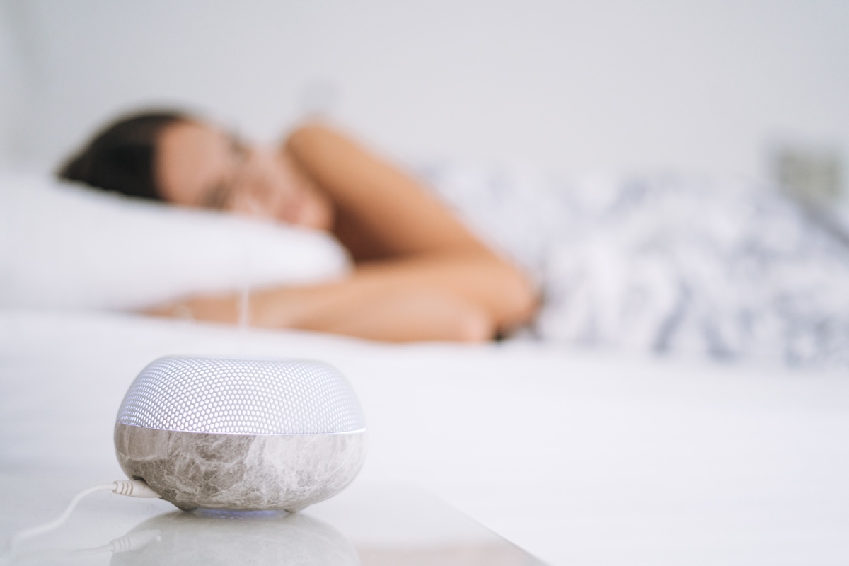 A woman sleeping with a white noise machine.