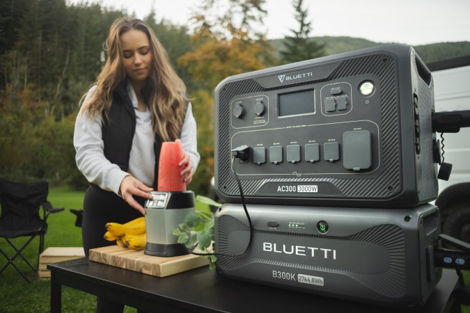 Woman using Bluetti AC300 and B300K to power a blender while camping