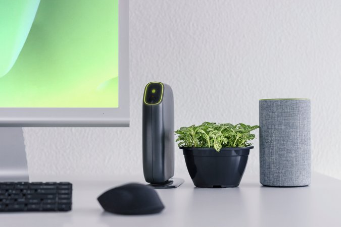 Technological office with personal assistant, computer, wifi and a green plant.