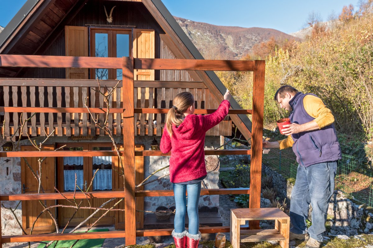 Cheerful Father and Daughter Painting Wooden Fence on Sunny Autumn Day