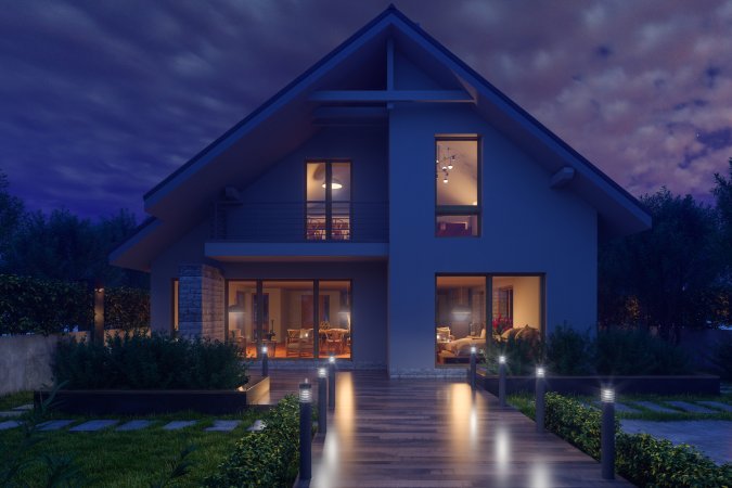 Modern house with wooden bridge out front lit up at night.