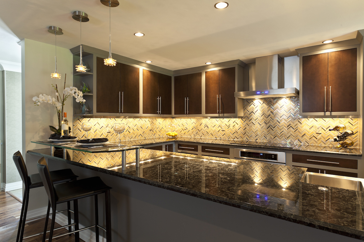 A galley kitchen with dark wooden cabinets features under cabinet lighting.