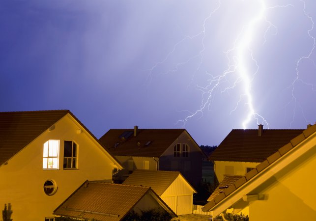 Lightning storm over houses in the evening.