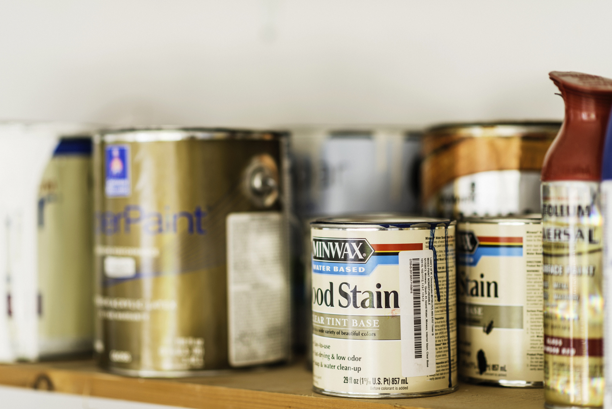 Assorted cans of paint, spray paint and wood stain.