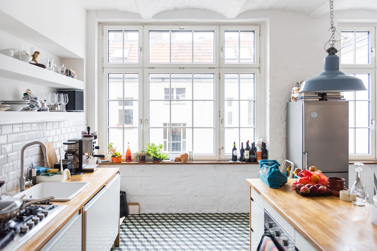 A galley kitchen with a large window features open shelving on one wall.