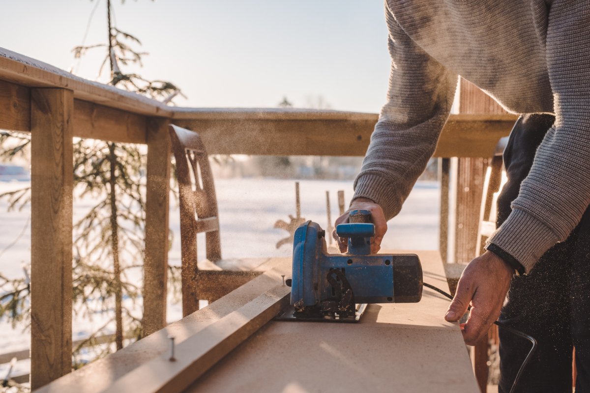 Man sawing wood for home improvement carpentry outdoors in cold winter.