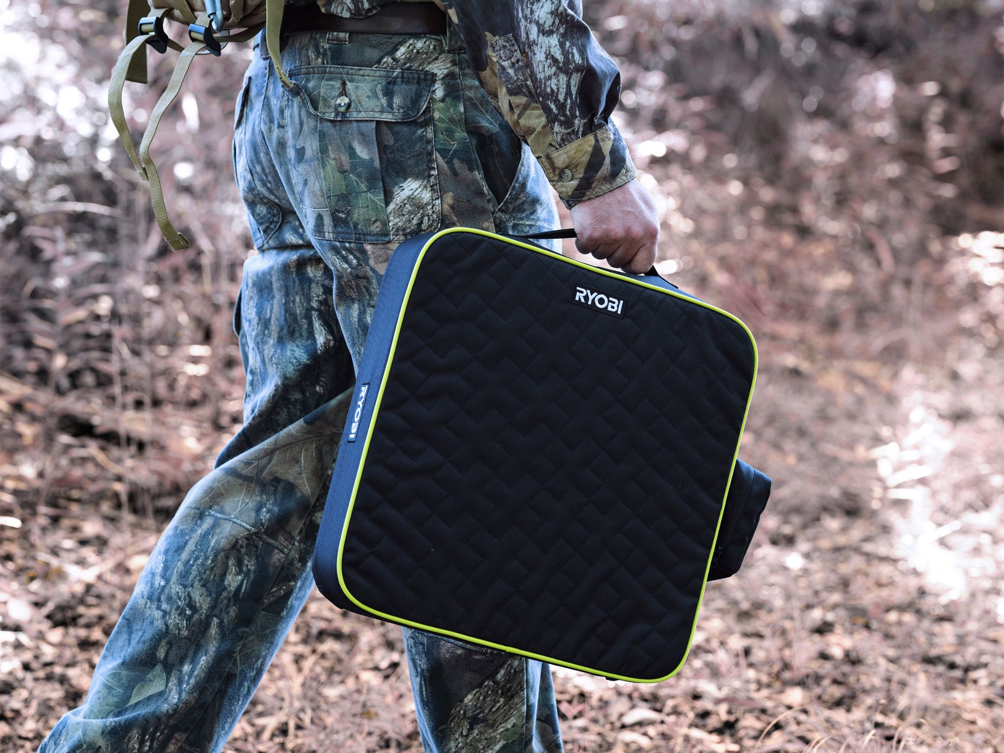 Hunter in camouflage carrying a Ryobi heated cushion kit