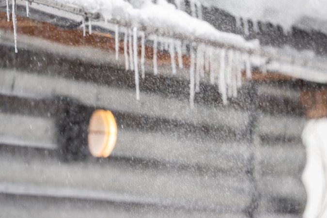 A severe snow storm rages outside of a cabin-style home.