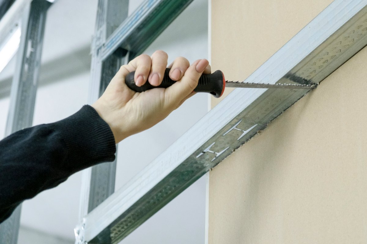 The girl saws off a piece of drywall with a special saw