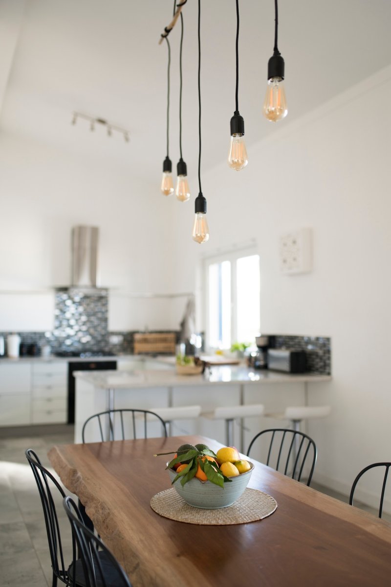 A modern kitchen with edison bulbs for lighting over the table.