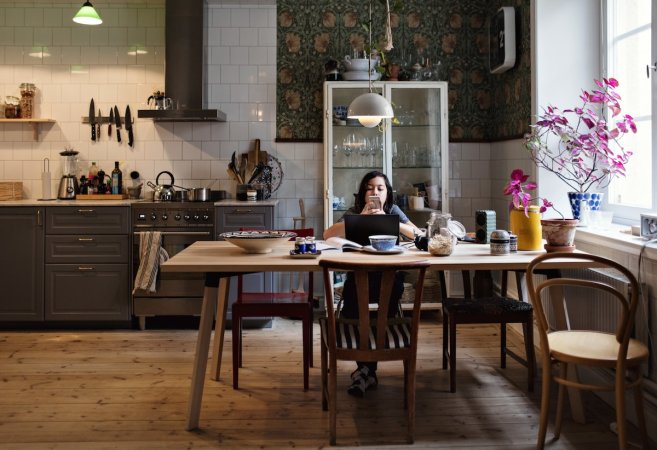 A girl sitting at a kitchen table with a pendant light overhead.