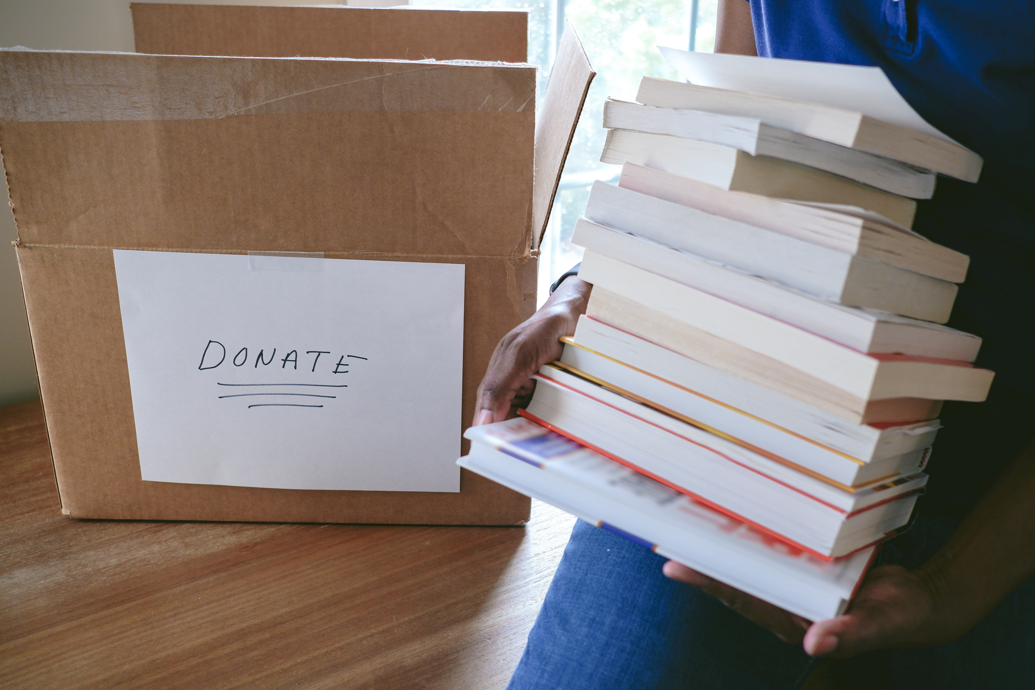 Close-up of unrecognizable woman packing books for donation.