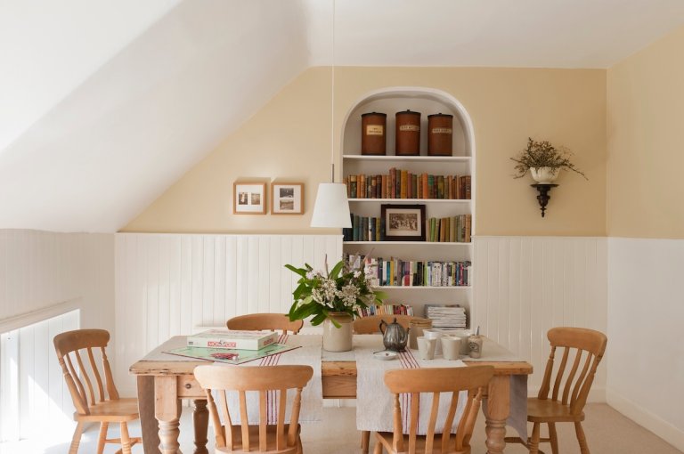 A built-in bookshelf displaying and storing books and decor in a dining room.