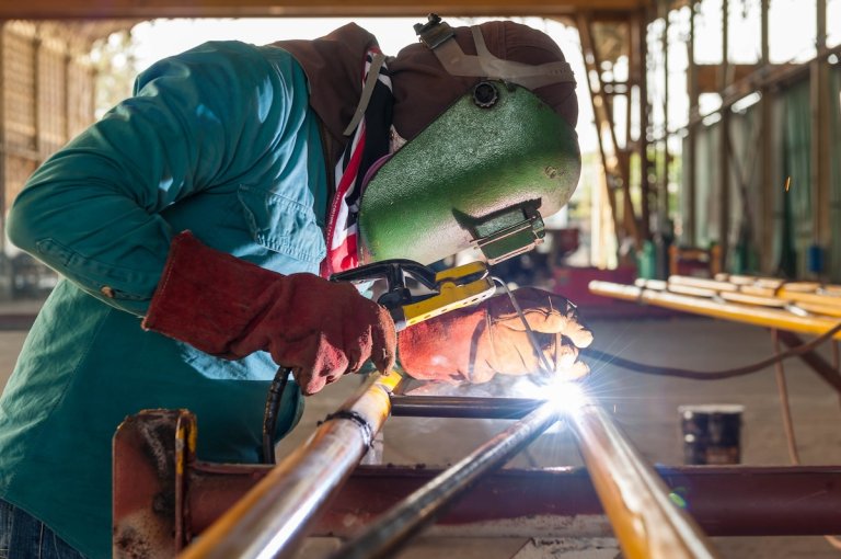 A welder using a stick welder to weld a metal project in the garage.