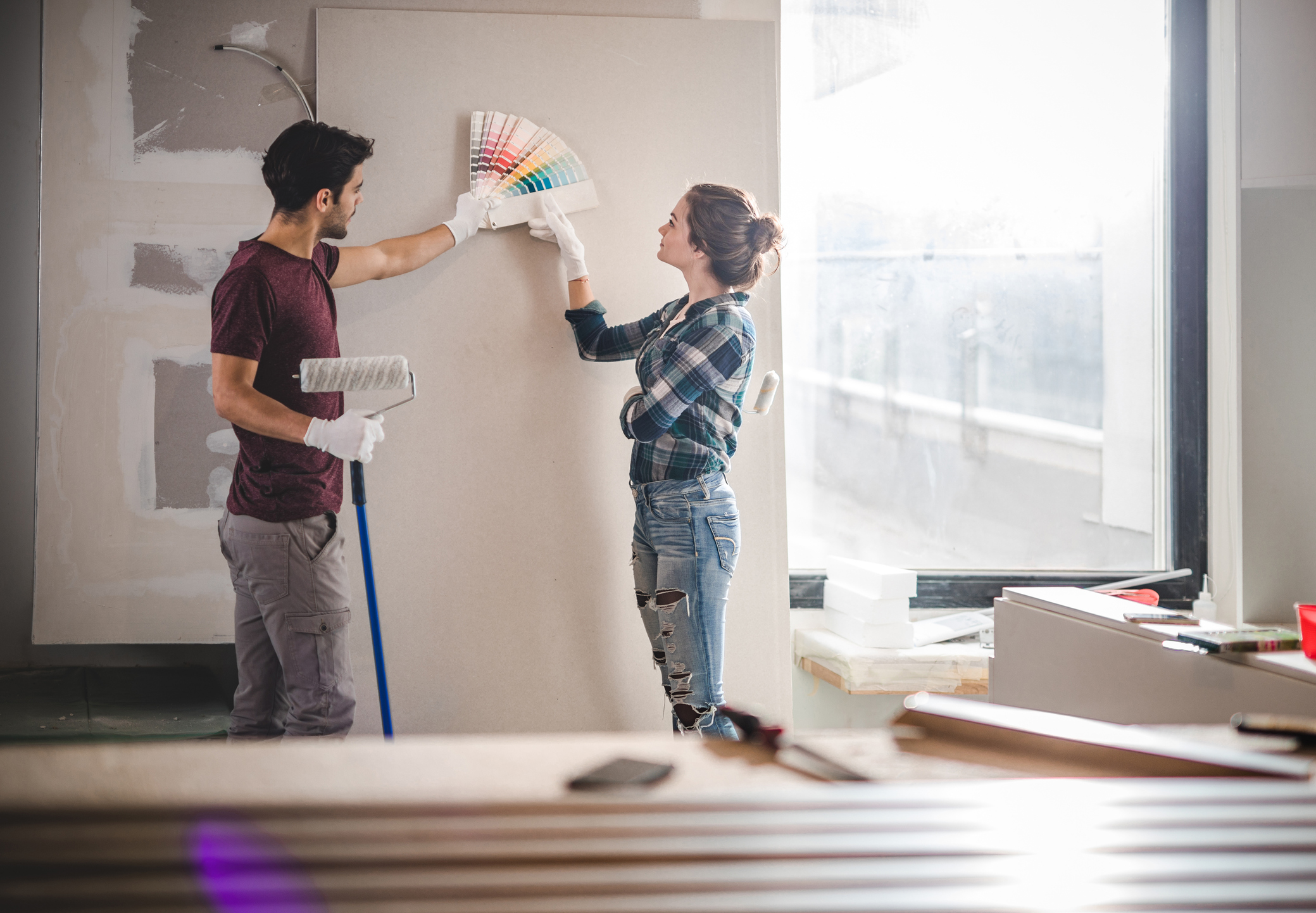 Young couple choosing the right color to paint a wall in their home.