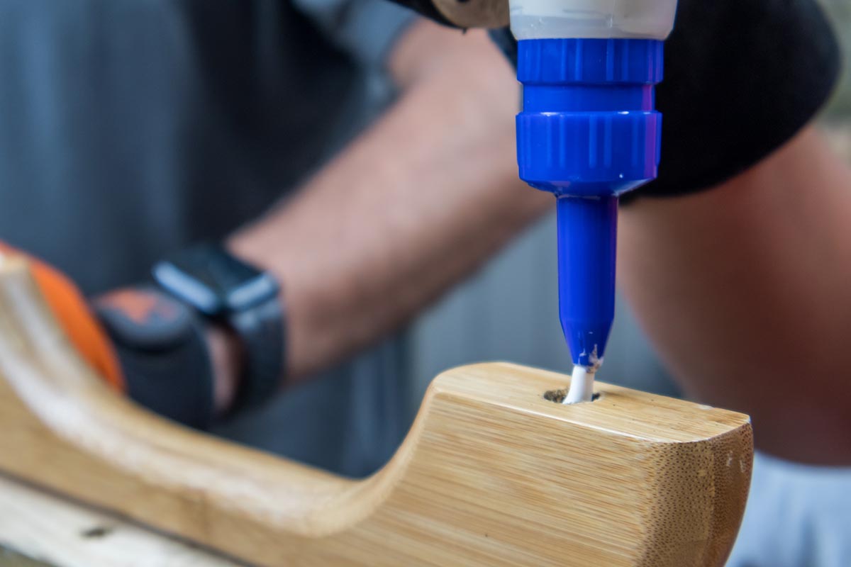 A person gluing a broken part of wood furniture.