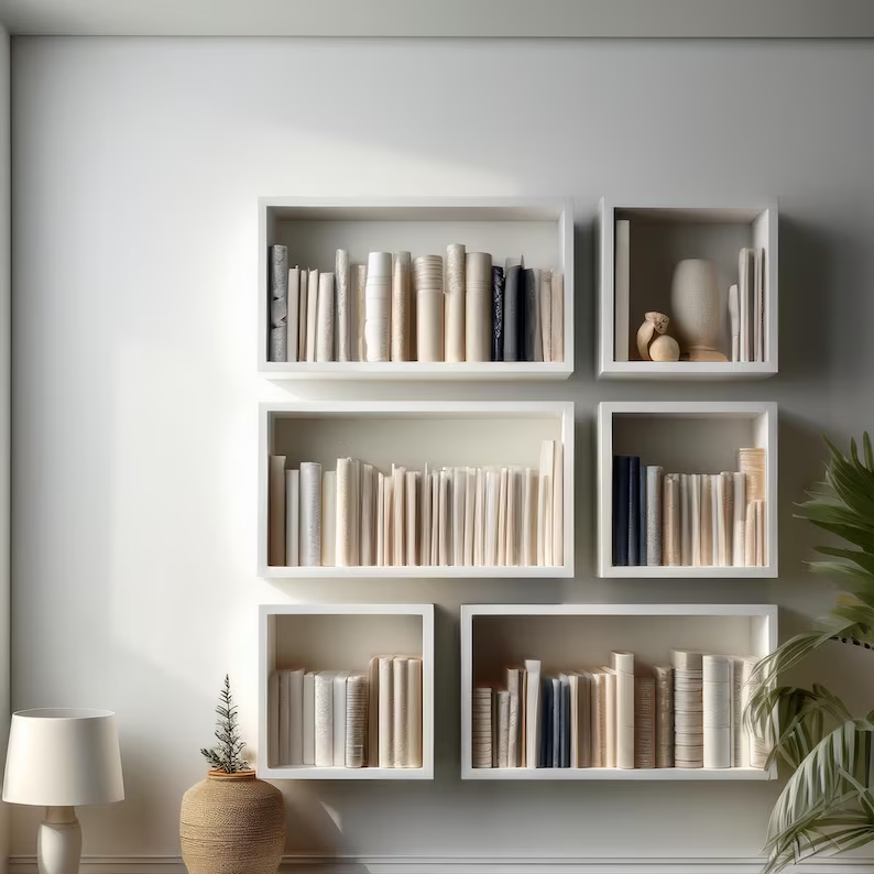 A set of built-in bookshelves holding monochromatic neutral display items and books on a wall.