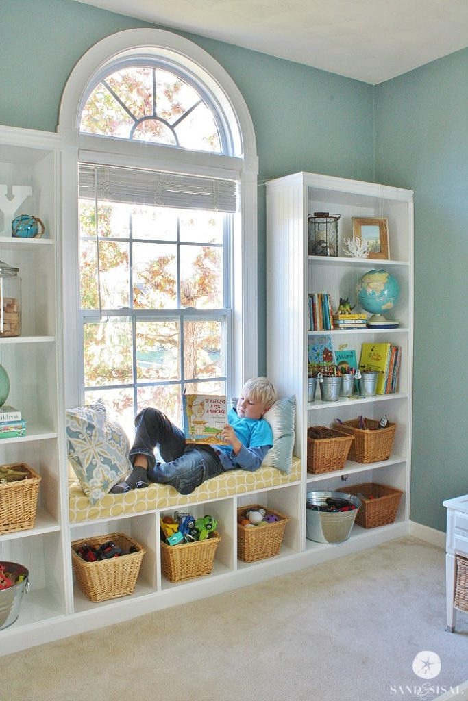 Built-in bookshelves around a window making a window seat with lots of storage and display space.