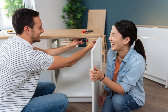 A young couple assembling kitchen cabinets in their new apartment.