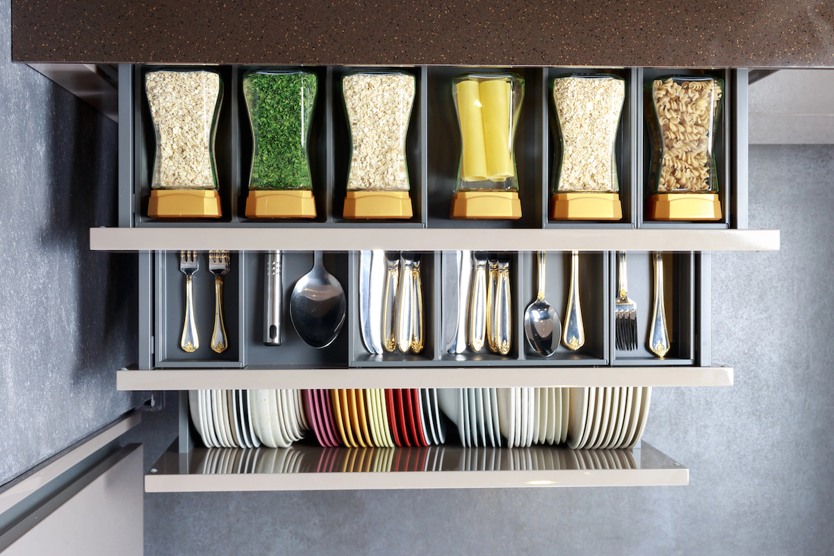 Birds-eye view of kitchen drawers with spices, utensils, and dishes tidily organized inside.