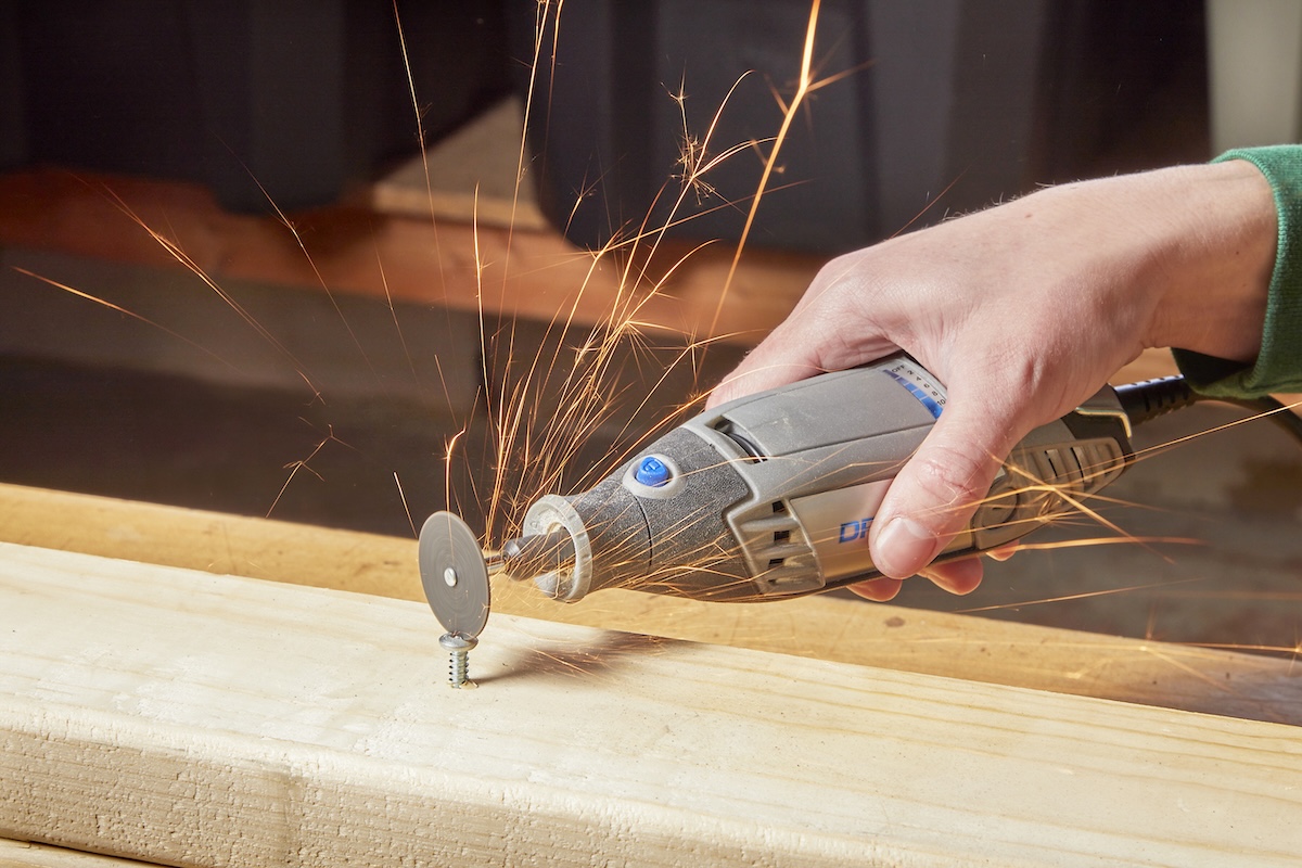 A person removing a stripped screw using a rotary tool.