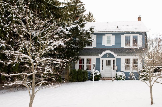 Blue colonial house covered in snow