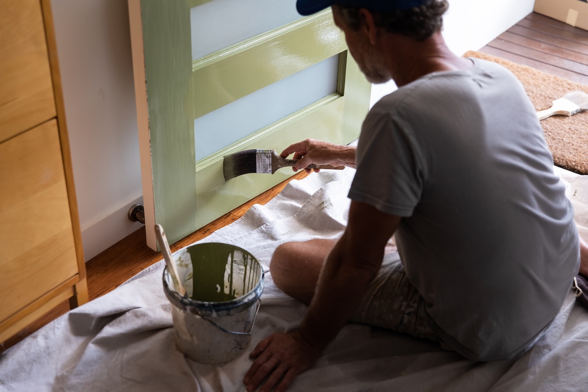 A homeowner painting over a front door repair made with all-purpose putty.