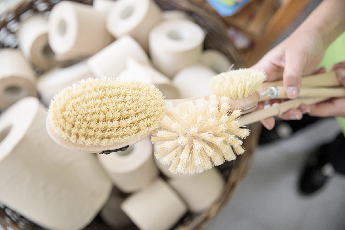 A person holding eco-friendly cleaning tools made with natural materials to avoid microplastics.