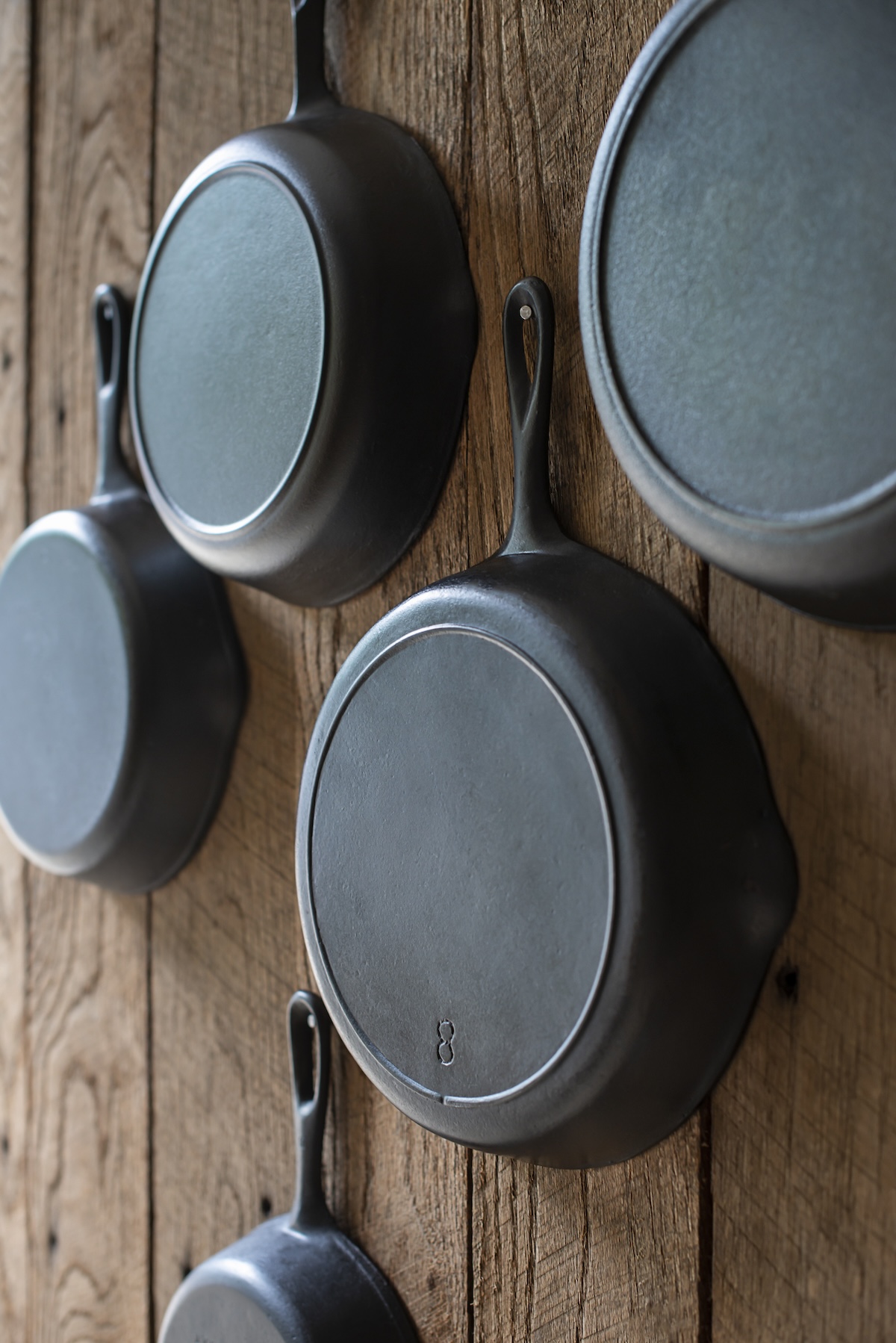 Several cast iron pans hanging in a kitchen to avoid microplastics when cooking.