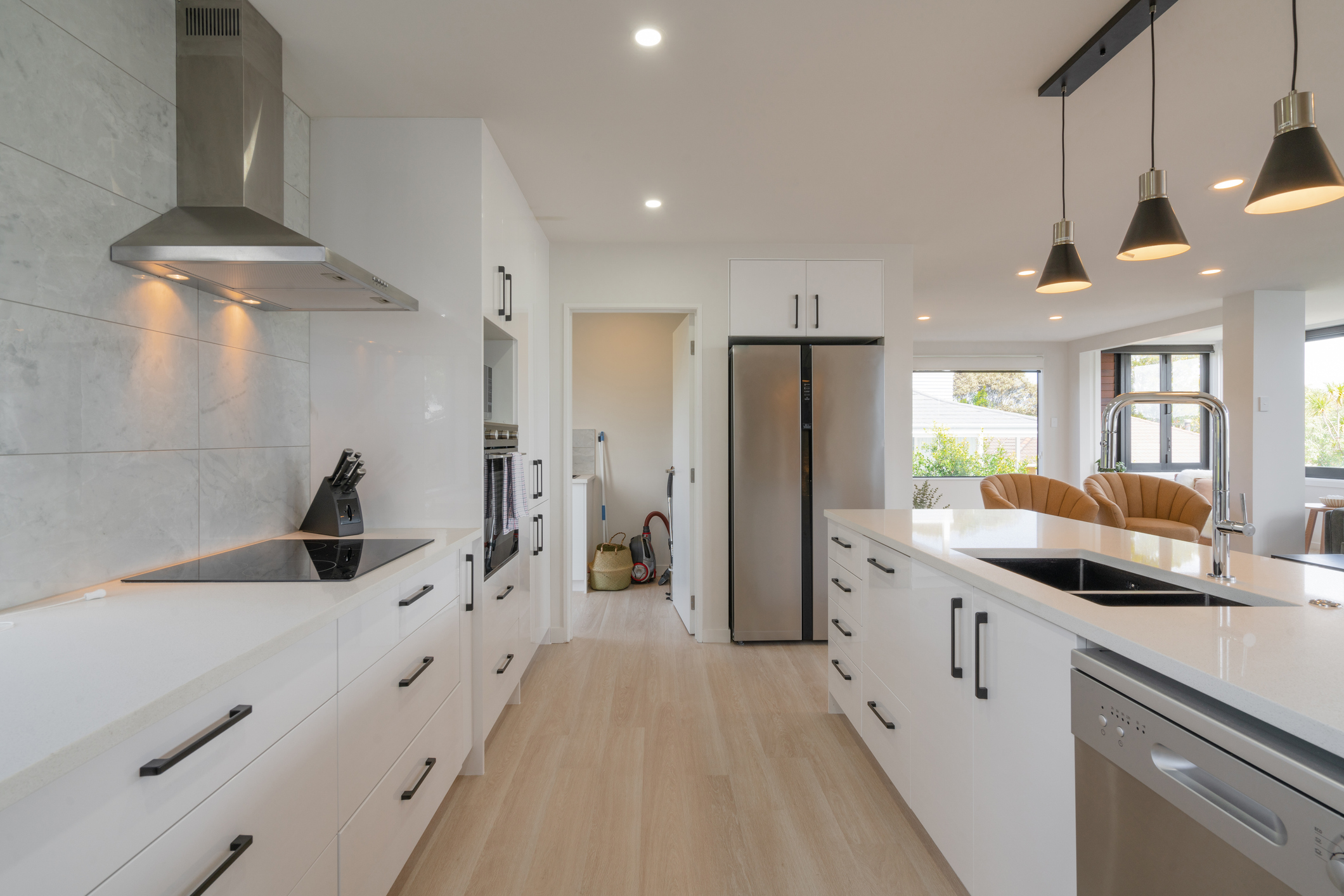 Modern kitchen with stainless steel appliances, white counters, and white cabinets.