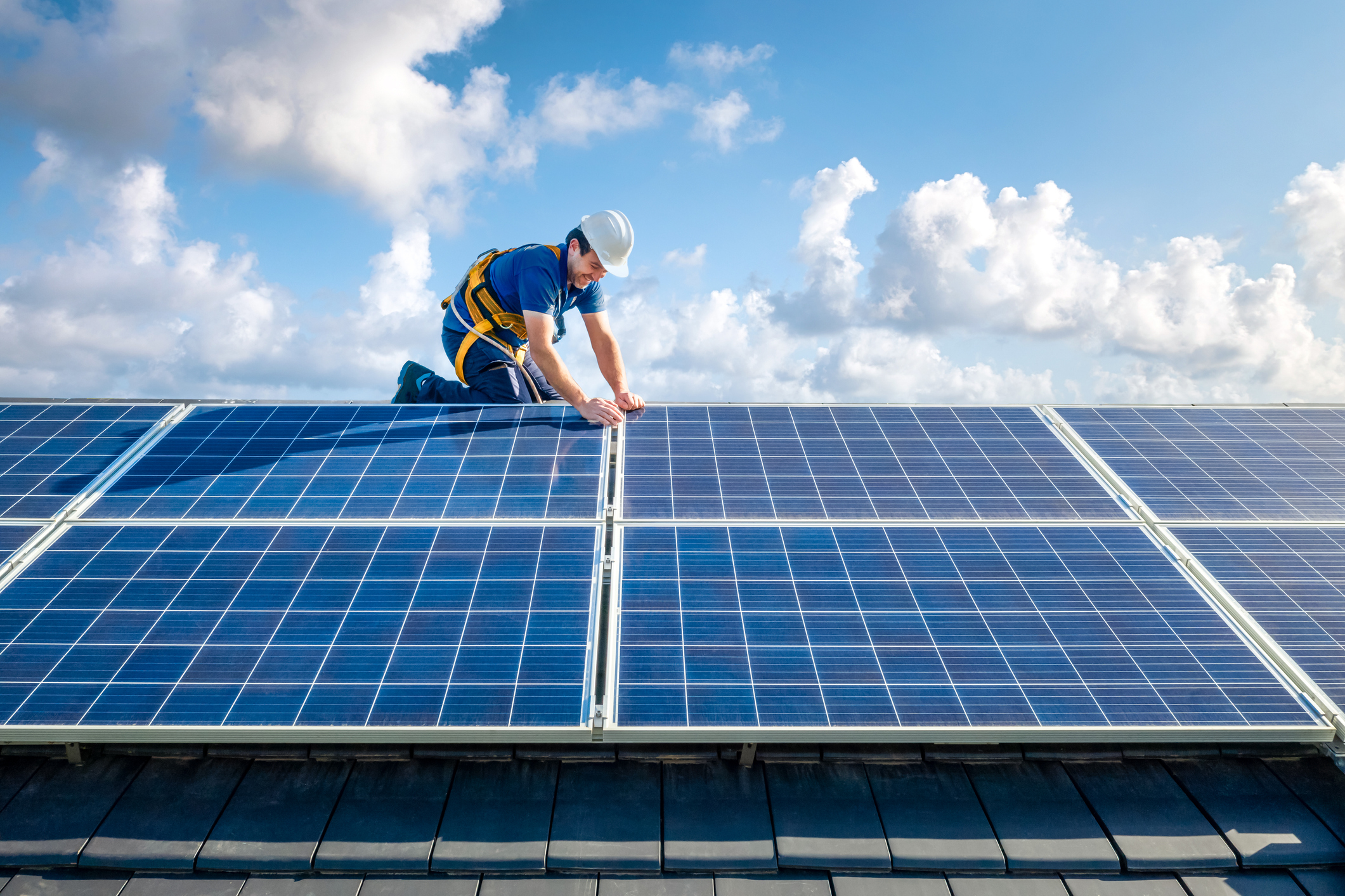 Male engineer in blue suit and protective helmet installing solar panels.