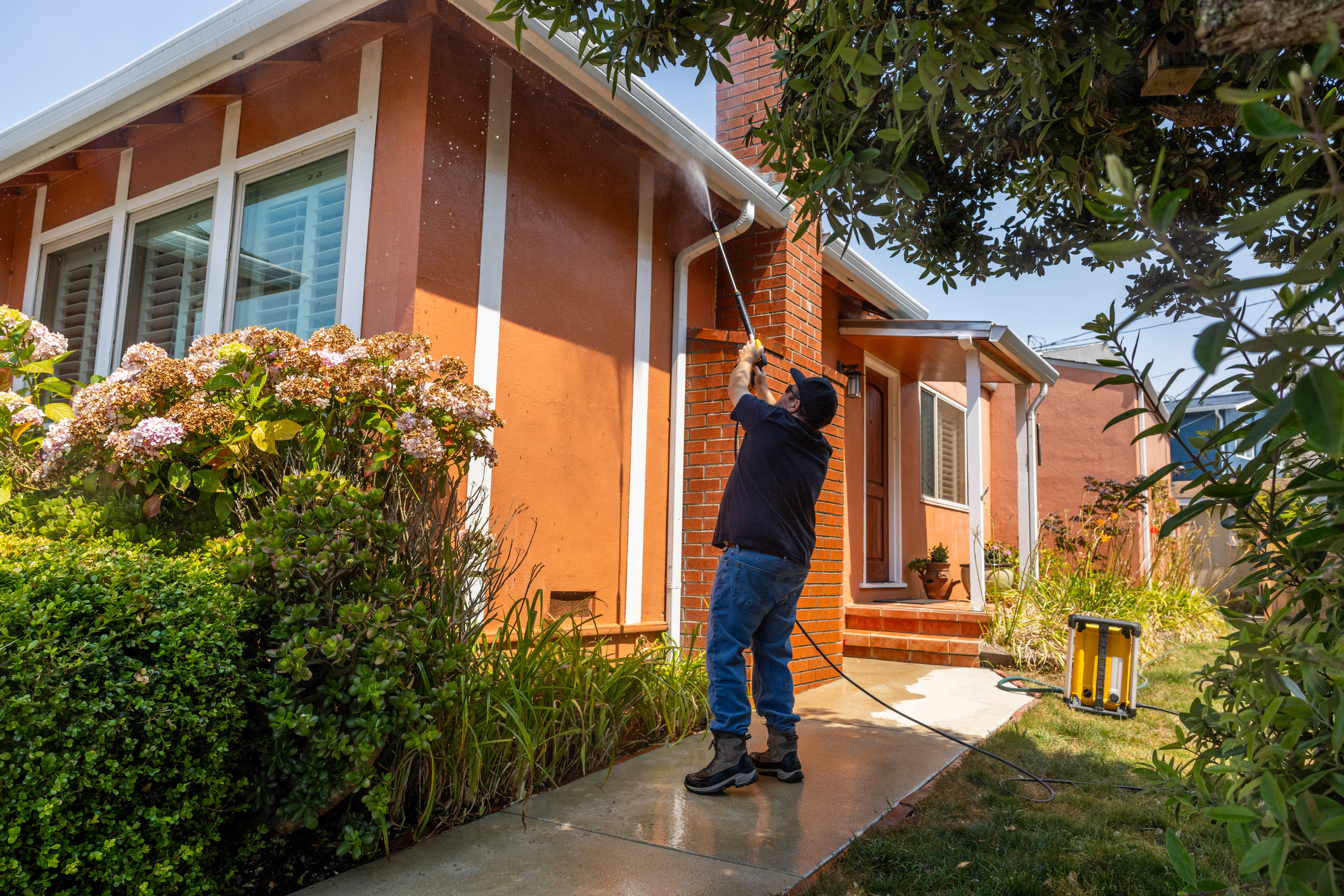 Man powerwashing the outside of a house.