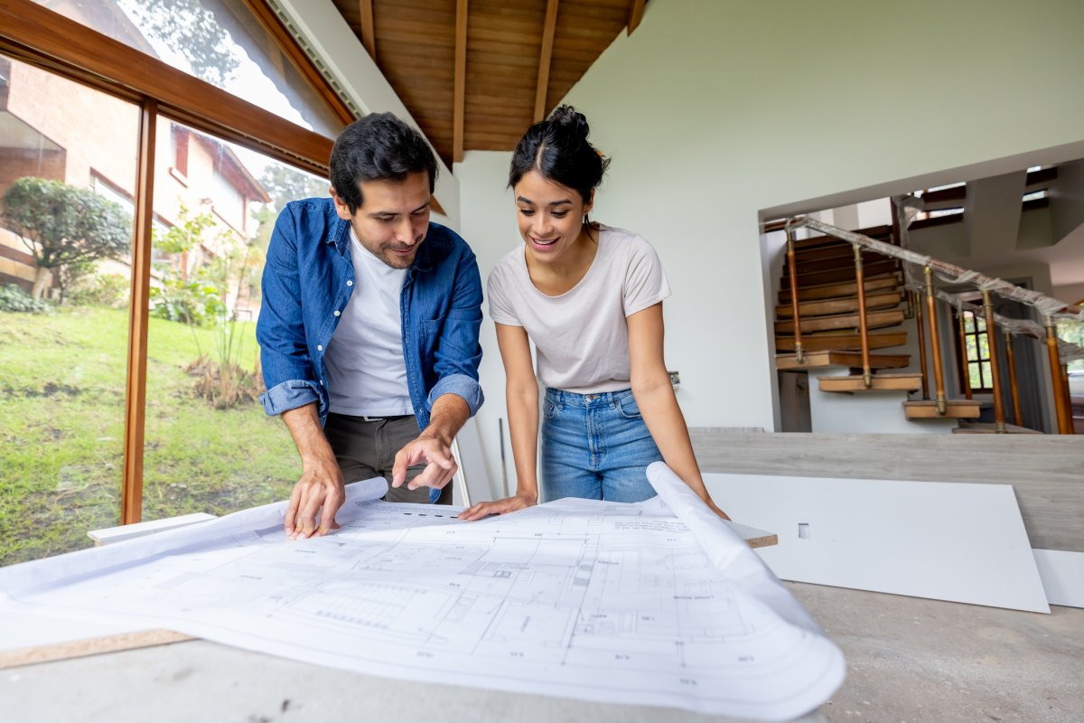 Happy couple looking at the blueprints while renovating their house.