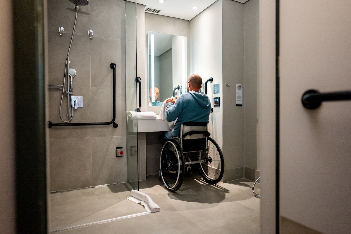 A person using the sink in an ADA-compliant bathroom.