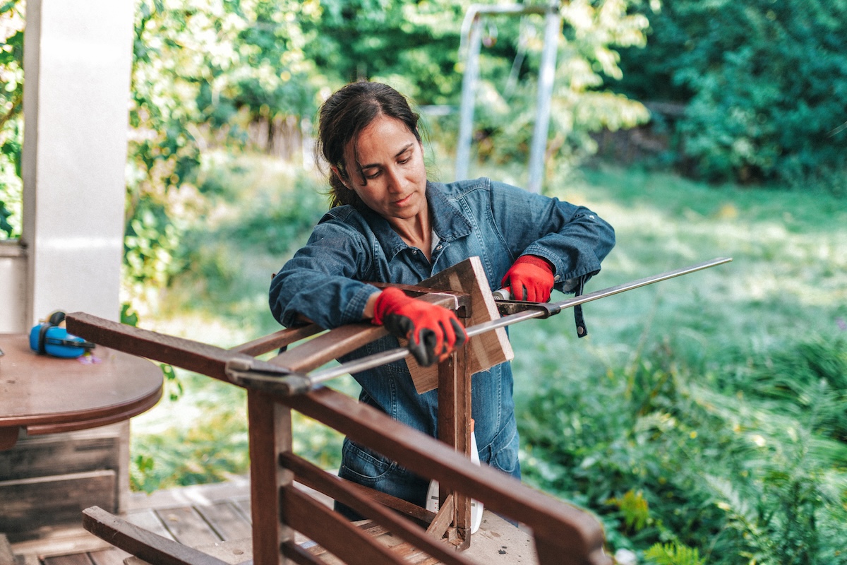 A person fixing a damaged wood chair with all-purpose putty.