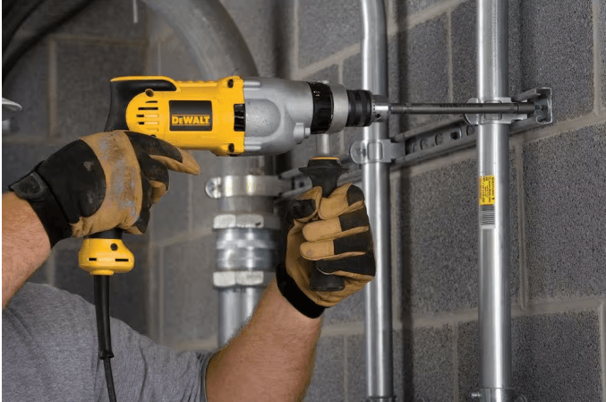 Dewalt corded hammer drill being used on concrete