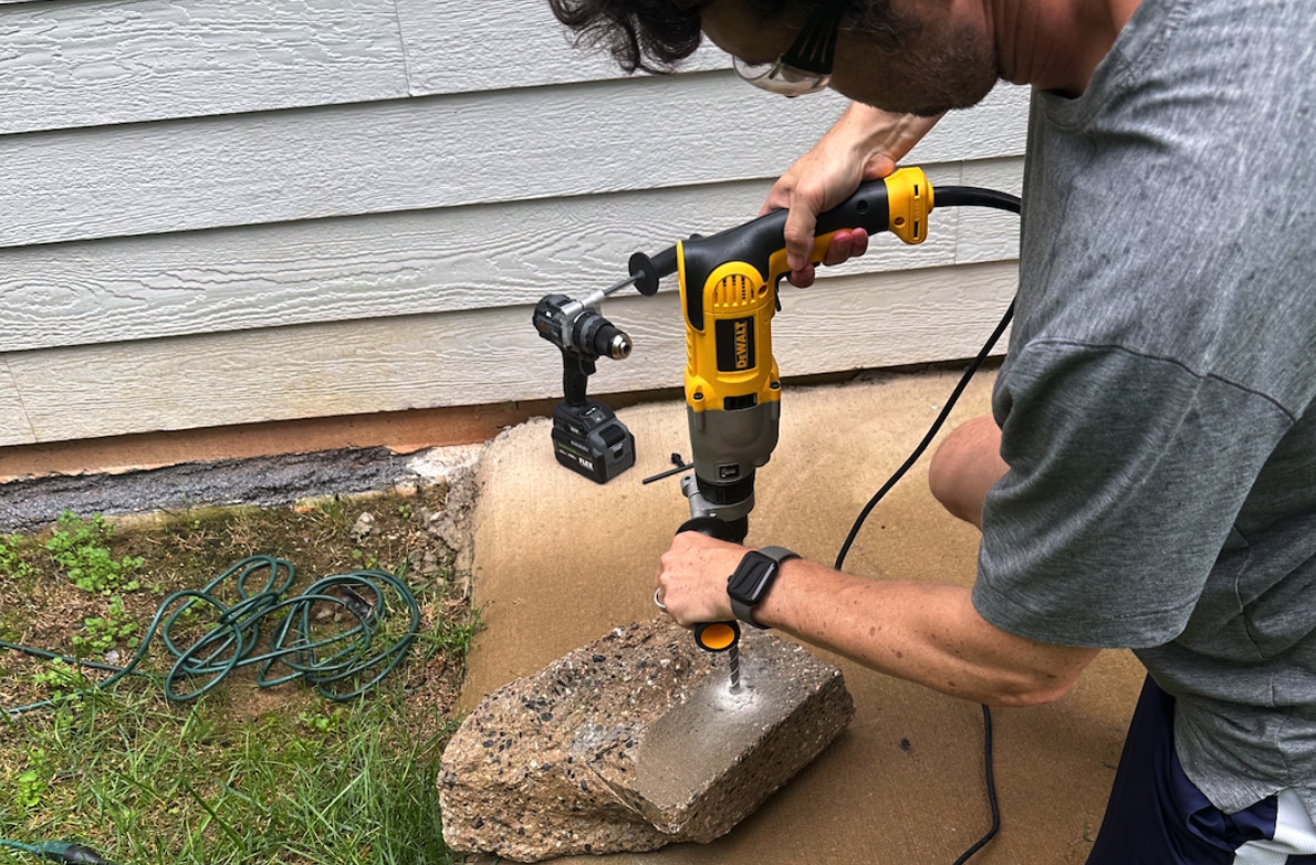 Dewalt corded hammer drill being used on concrete