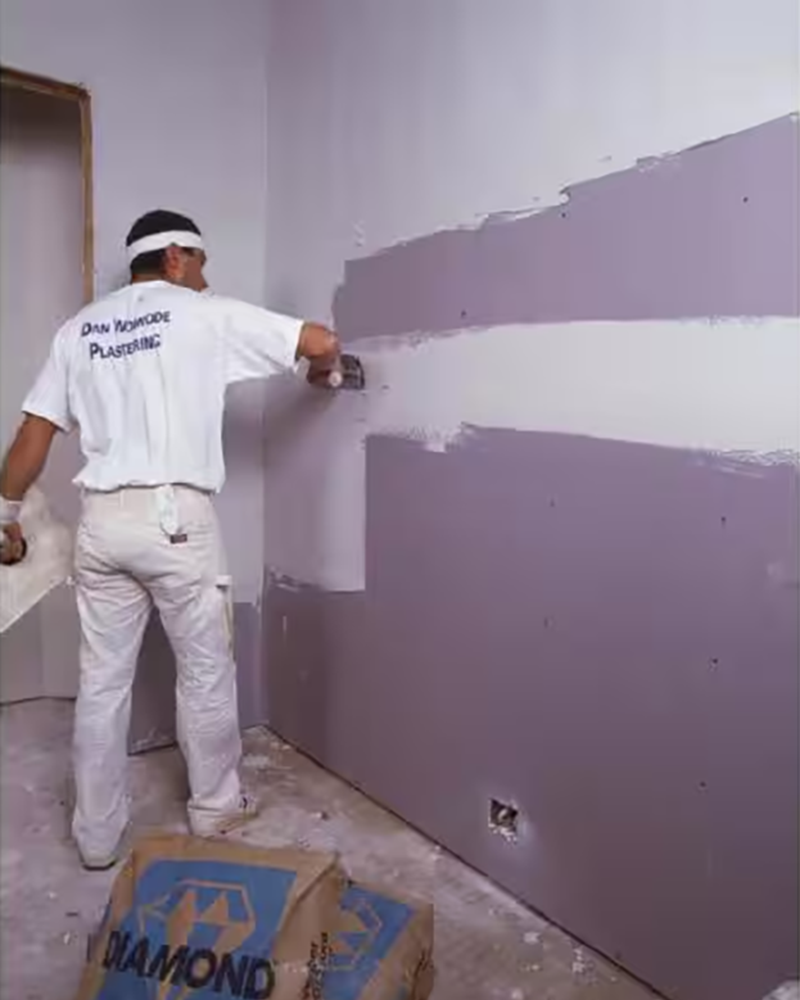 A contractor installing blue board drywall made for plaster.