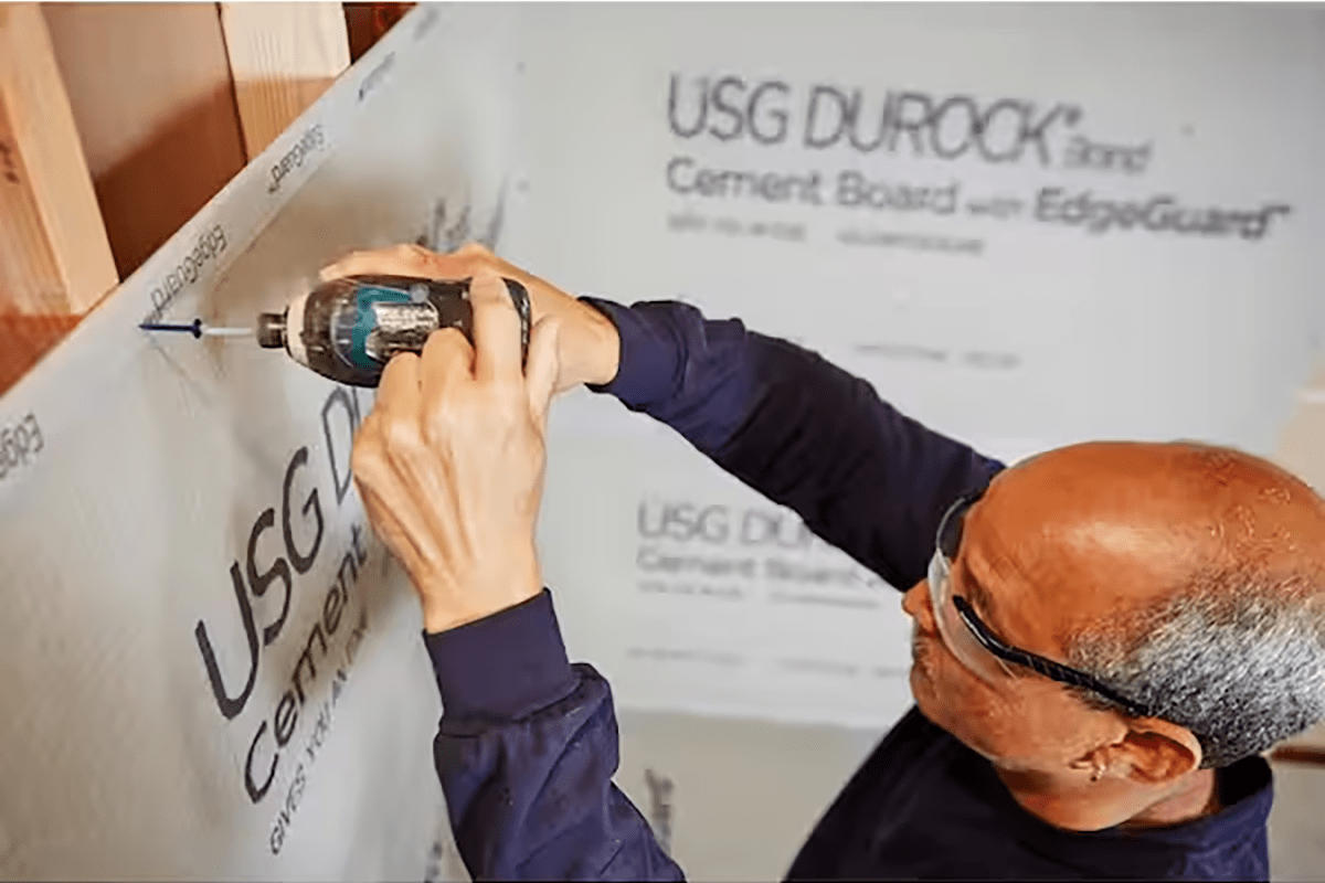 A DIYer installing cement board sheets in a home bathroom remodel.